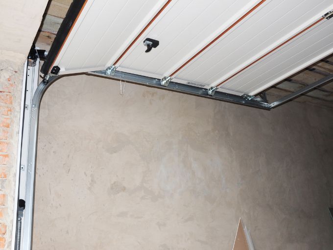 Close-up of a modern belt-drive garage door opener motor mounted to the ceiling, highlighting the internal components that can fail over time.