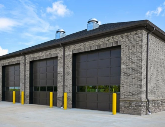 Heavy-duty sectional commercial garage doors featuring high-clearance tracks and integrated vision lites for warehouse and industrial use.