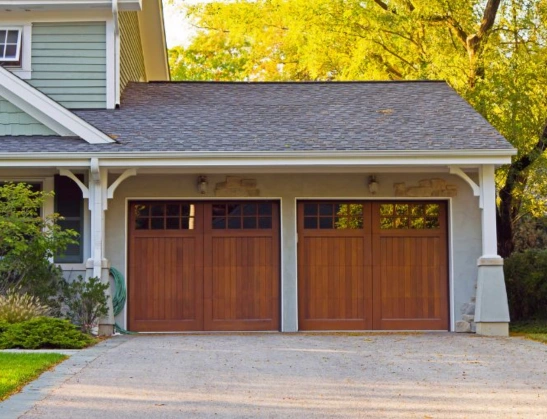 Two custom wood-look carriage house garage doors with vertical plank panels and divided lite windows installed by Greer Garage Doors.