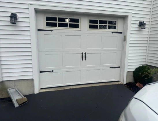 White carriage house garage door featuring black decorative strap hinges, handles, and Stockton window inserts by Greer Garage Doors.