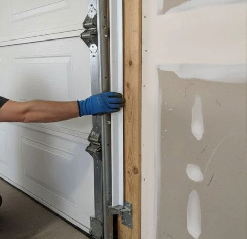 Close-up of a garage door technician installing a side weatherstrip seal to prevent drafts, moisture, and pests from entering the garage.