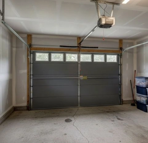 Interior view of a gray modern flush-panel garage door with a top row of clear windows and professional overhead track system by Greer Garage Doors.