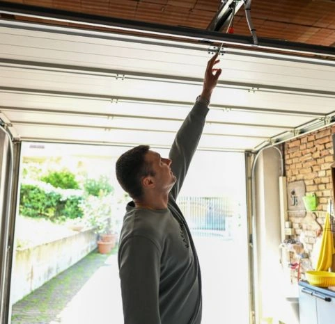 Garage door opener repair in Greer, SC, featuring a technician troubleshooting a residential sectional door system and overhead motor.