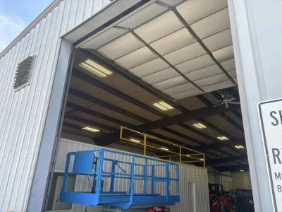 Commercial overhead door installation for a large industrial warehouse featuring a high-lift track system by Greer Garage Doors.